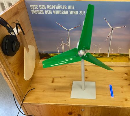 Windrad-Station der Klimaversum-Ausstellung mit Miniaturwindrad, Kopfhörern und Fächern