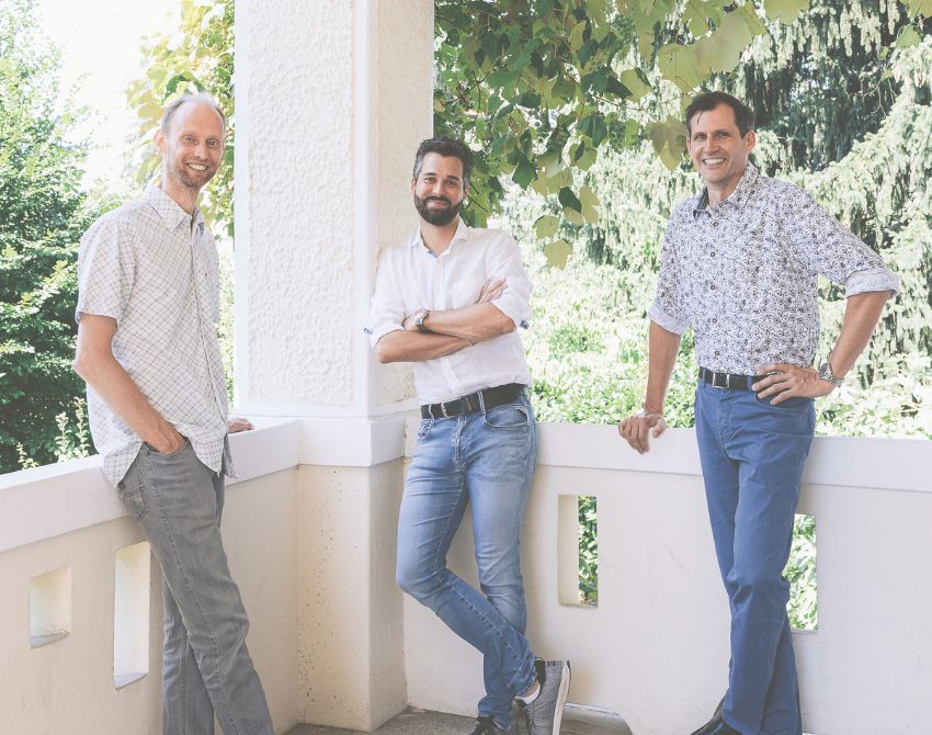 Drei Männer lehnen an Mauer