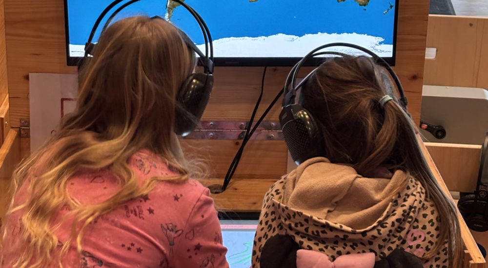 zwei kinder sitzen vor bildschirm und zeichnen