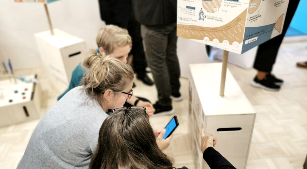 3 Personen schauen sich den Klimaladen an