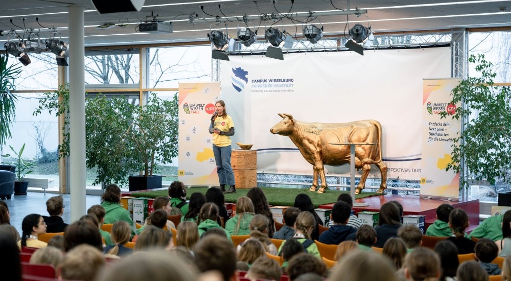 Ein Mädchen spricht auf einer Bühne vor einem jungen Publikum