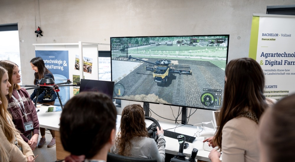 mehrere Jugendliche schauen einem Mähdrescher-Simulator zu