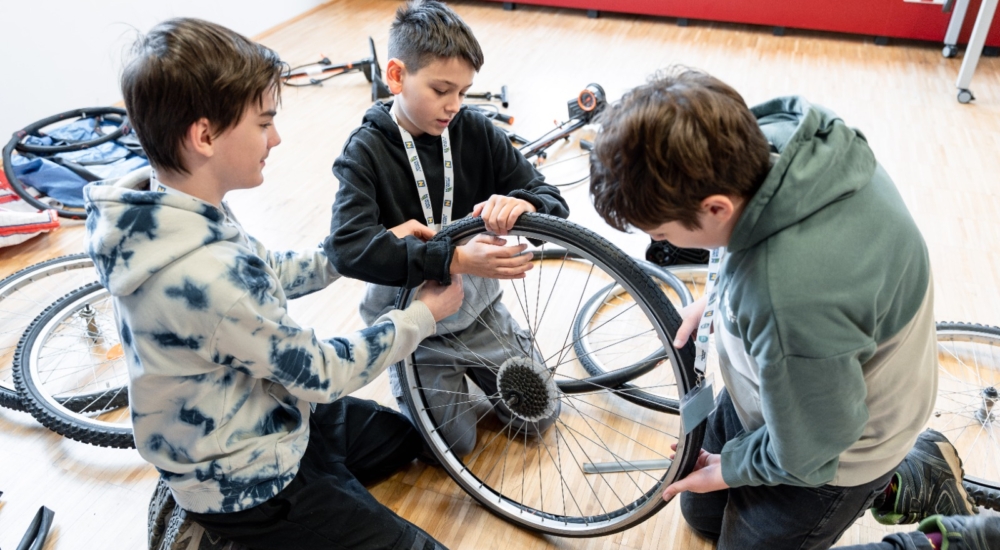 drei Jungs wechseln einen Fahrradreifen