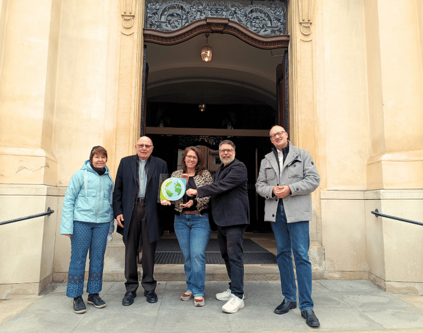 Gruppenfoto vor der Kirche mit Klimabündnis Tafel