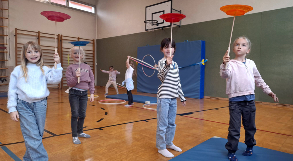 Kinder beim jonglieren mit einem Stab und Tellern