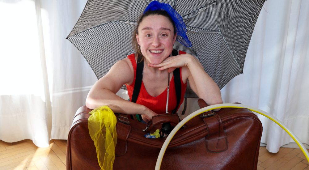 Klimazirkus-Pädagogin lacht in die Kamera und präsentiert ihre Requisiten